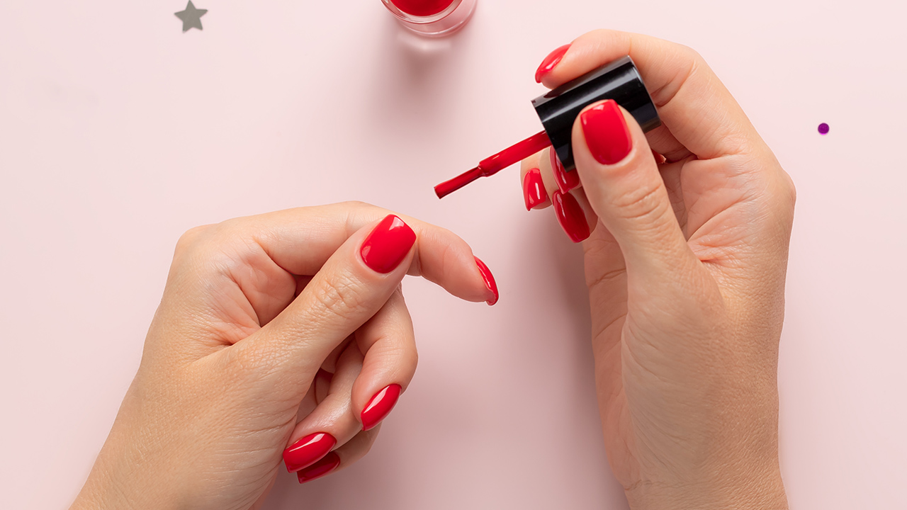 manos pintándose las uñas de rojo